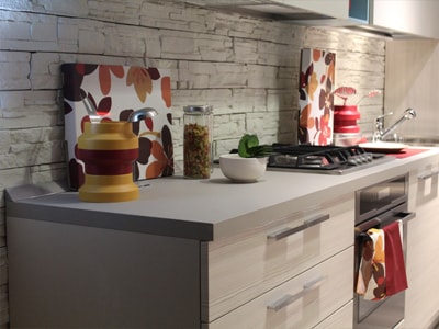 Moderne Küchenzeile mit Gasherd, Steinwand und bunten Küchenaccessoires.