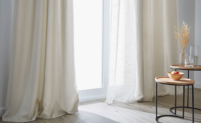 Tagelicht kommt durch ein Fenster, leicht verdeckt durch weiße Vorhänge.